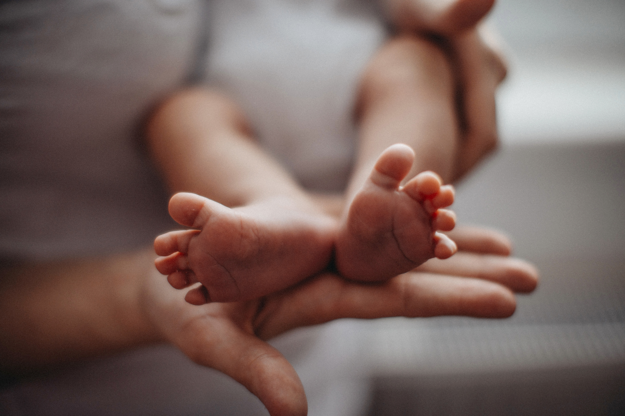 Unrecognizable mother with newborn baby daughter, legs and hand